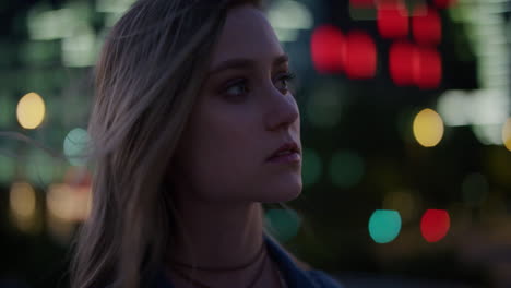 retrato de cerca hermosa joven rubia mujer con aspecto pensativo disfrutando de la tranquila vida nocturna urbana en la ciudad por la noche el viento soplando el cabello cámara lenta serie de personas reales
