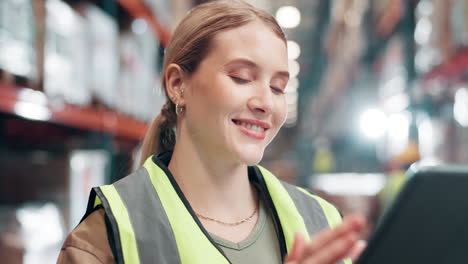a woman wearing a safety vest in a warehouse using a tablet