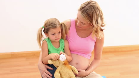 blonde pregnant woman sitting with her little girl