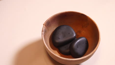 professional heating up massage stones in a wooden cup