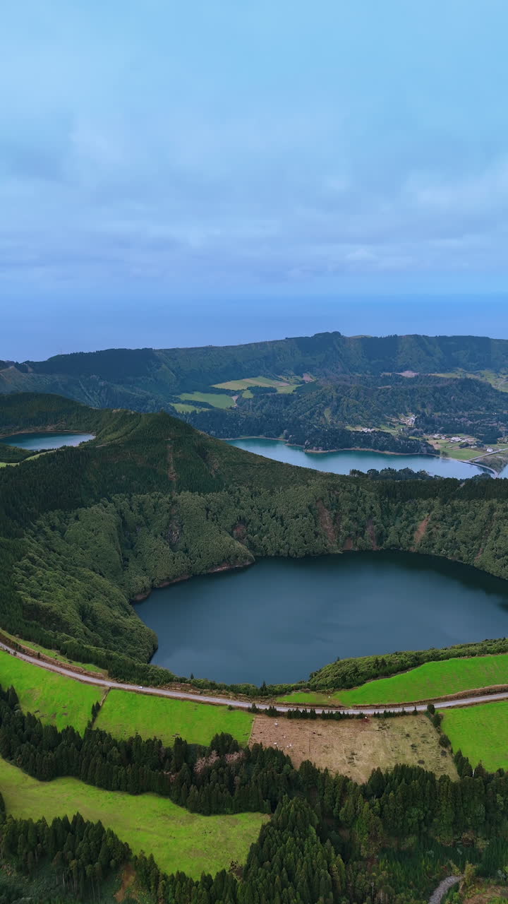 Coming closer to a lake in the sleeping volcano crater. Highway passes along the top edge of the mount. Vertical video.
