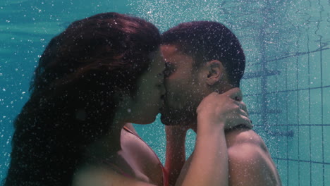 young couple kissing underwater in swimming pool enjoying intimate kiss romantic lovers submerged in water floating with bubbles in passionate intimacy