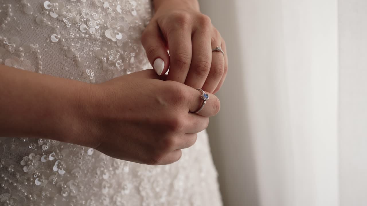 Graceful hand adjusts gemstone jewelry amid beaded white elegance