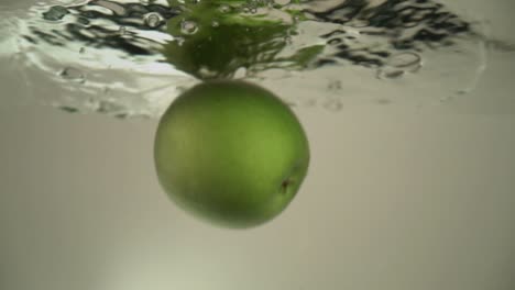 an apple is dropping into the water and staying at the water surface