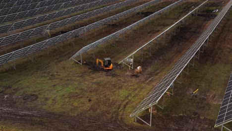 excavator digs underneath solar power panels in the solar power plant