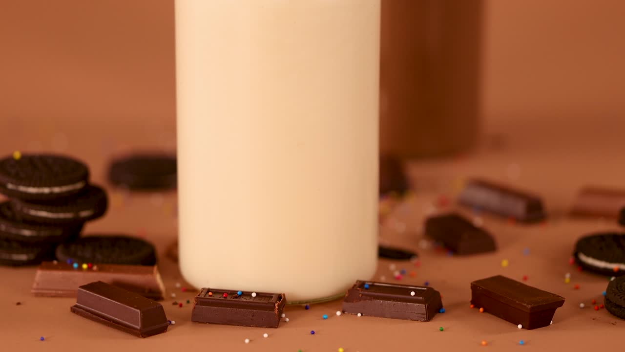 Vanilla milkshake with whipped cream topping, chocolate pieces, cookies, and chocolate milkshake in warm lighting
