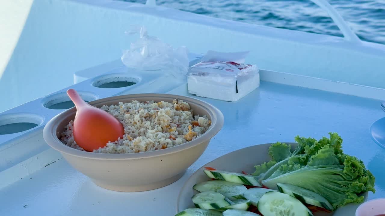A vibrant meal on a boat in Phuket, Thailand, featuring fresh fish, vegetables, and soup under bright daylight