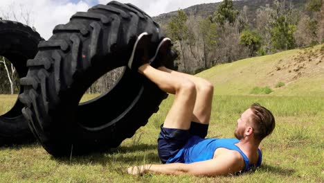 Fit-man-exercising-with-heavy-tyre-during-obstacle-course