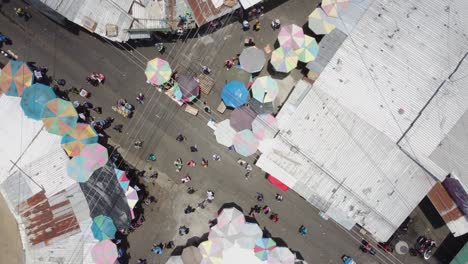 Rotating-aerial-descends-to-street-market-intersection,-San-Salvador