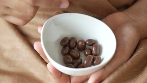 persona comiendo almendras cubiertas de chocolate