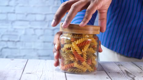 man hand taking dry italian pasta from a jar .