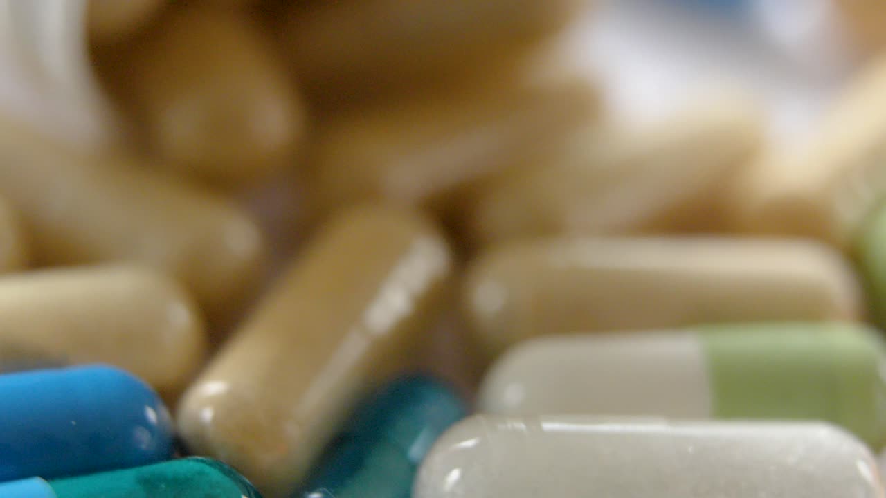 various drug capsules and pills lying in a mixed pile beside their bottles