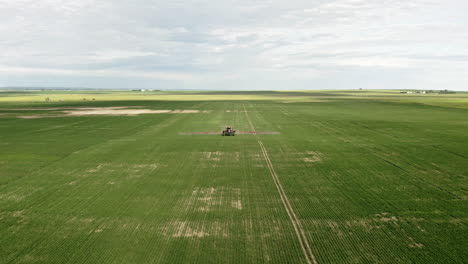 maquinaria agrícola rociando campos de trigo verde en saskatchewan, canadá - drone aéreo