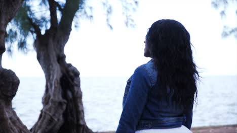 African-American-woman-walking-in-a-white-dress-and-jacket-in-the-woods-through-trees-towards-the-ocean-Cinematic-4k