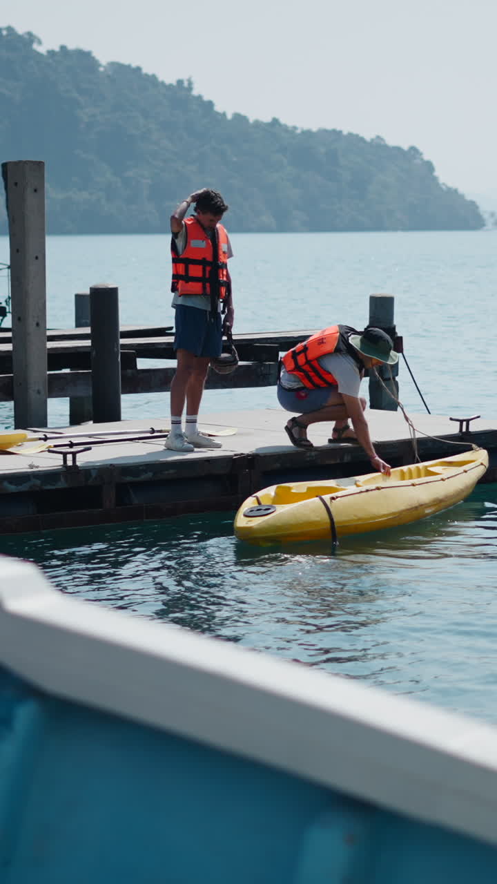 Due uomini che preparano un kayak su una banchina