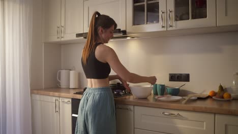 woman cooking breakfast in a light kitchen