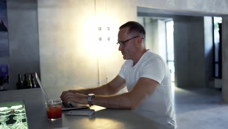 hombre de negocios sonriente trabajando en una computadora portátil en el bar. hombre profesional escribiendo en el teclado de la computadora portátil en el lugar de trabajo del bar. retrato de hombre de negocios positivo mirando la pantalla de la computadora portátil en el interior