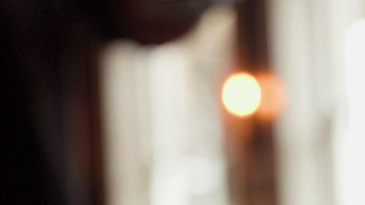 Out-of-focus man lifts pint glass in warmly lit pub, shallow depth, soft bokeh background