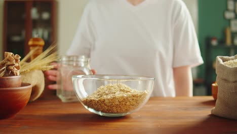 person pouring oats into a bowl in the kitchen