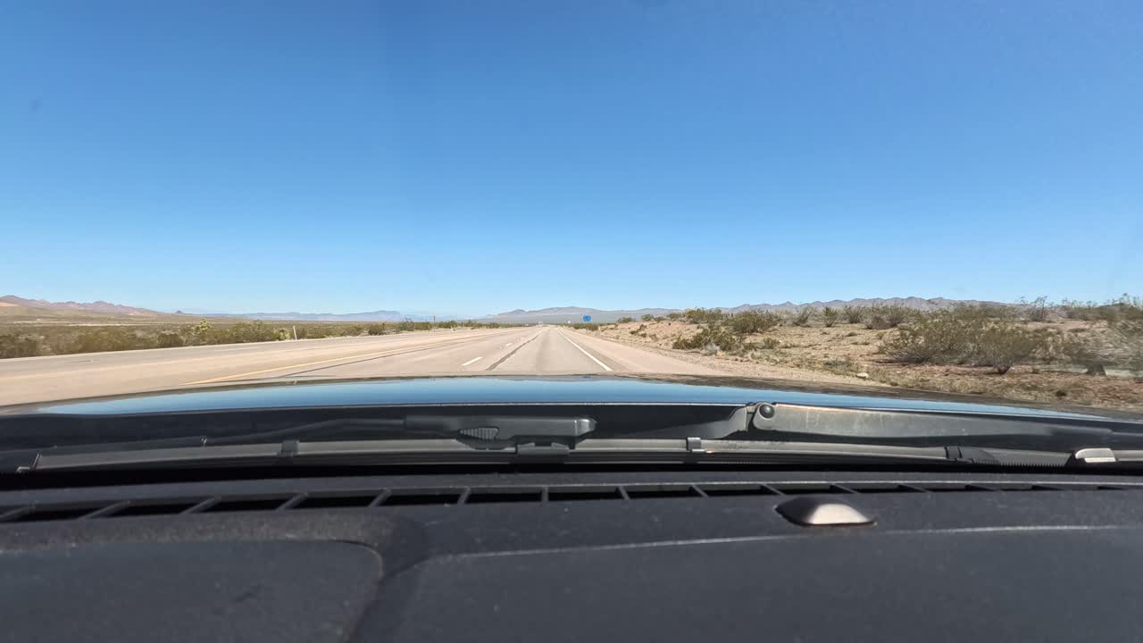 mirando a través del capó de un coche mientras conduce la autopista interestatal en los desiertos de california dirigiéndose hacia la frontera de arizona con montañas en el fondo