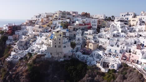 aerial: slow panning drone shot of oia in santorini, greece during golden hour