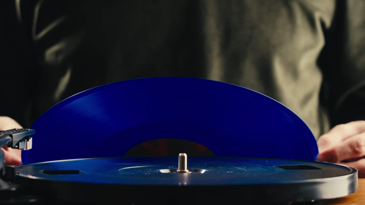 Persona che posiziona un disco in vinile blu sul giradischi e abbassa la puntina
