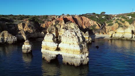 aerial orbits golden sea stacks on ponta da piedade coastline, portugal