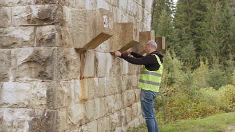 worker inspecting stone wall