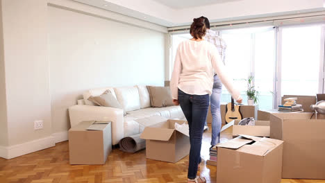 attractive couple moving boxes into their living room