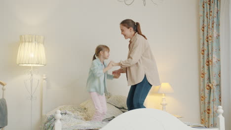 mother and daughter dancing on bed