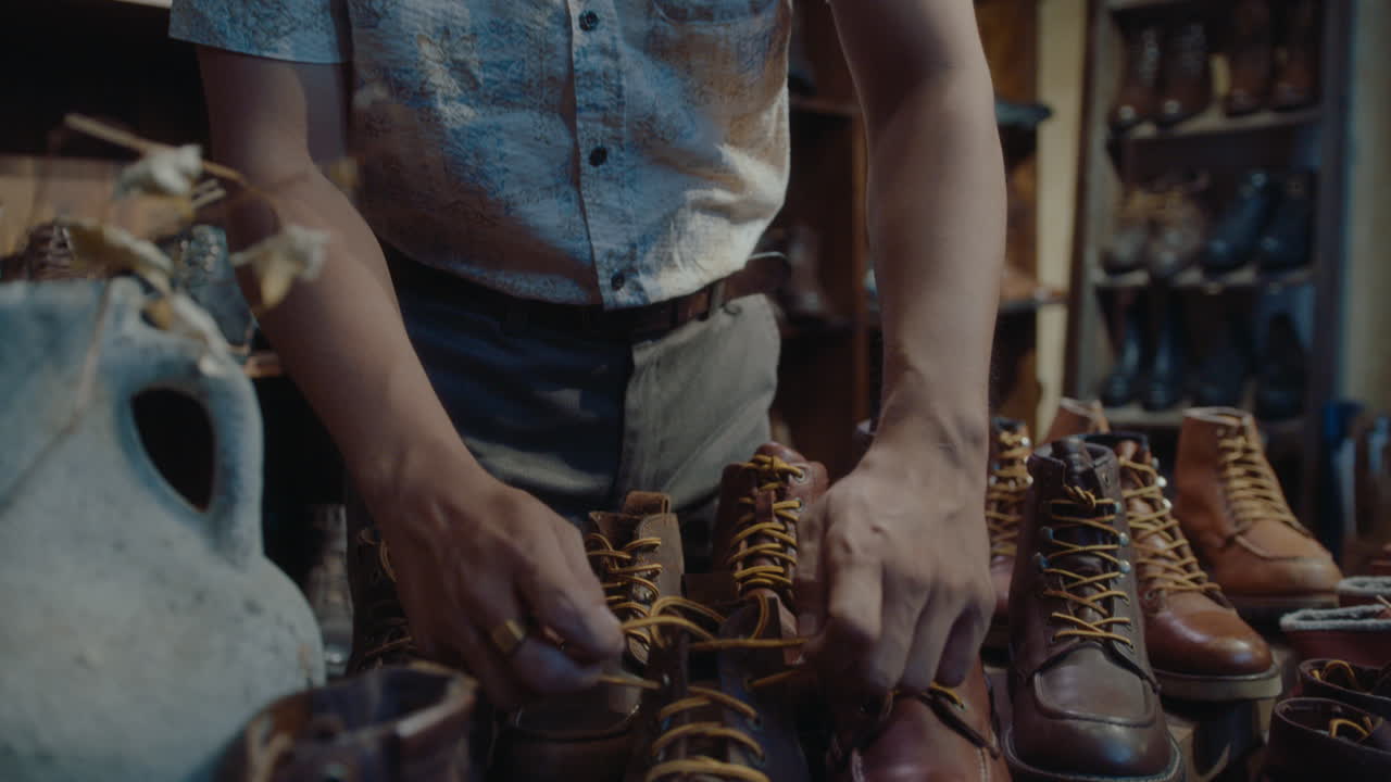 Asian Cobbler Tying Shoelaces on Old Leather Boots in Vintage Store