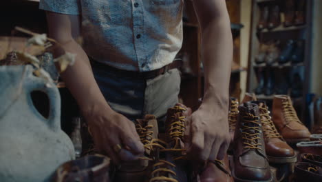asian cobbler tying shoelaces on old leather boots in vintage store