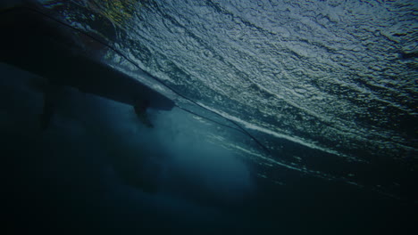 longboard surfer sits back on wave as it crashes and breaks past