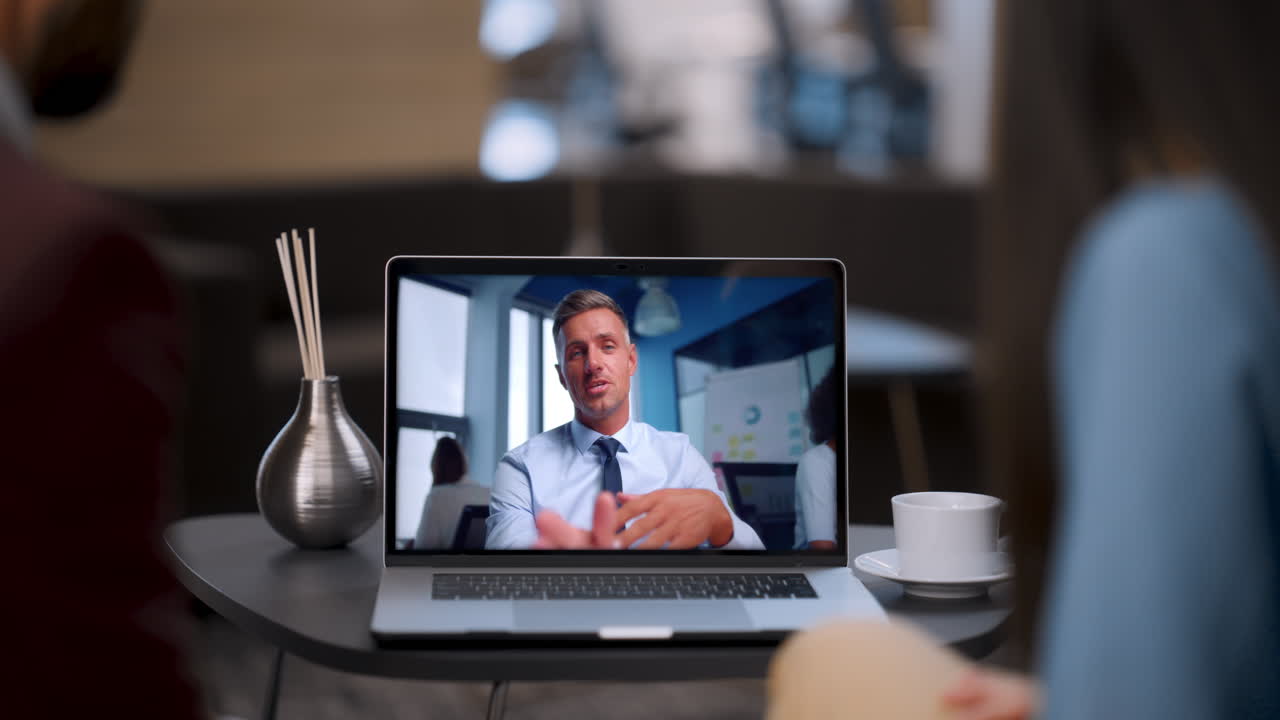 Two colleagues talking remotely with boss using laptop in restaurant close up