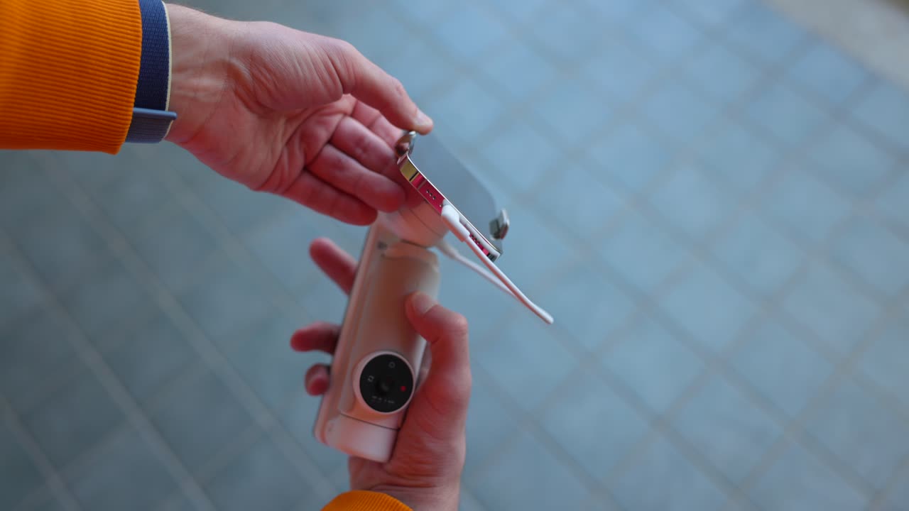Person connecting a mobile phone to a compact video stabilizer