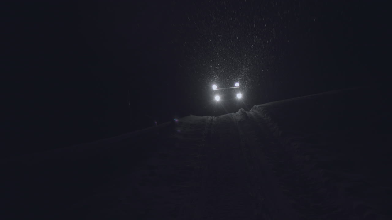 Half-track driving in the night in Jotunheimen in Norway. The half-track has skies in front. Its night and the snow are falling. Filmed on a gimbal in 4k. This is a slow-motion clip.