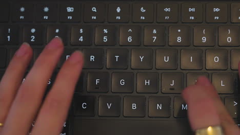 top-down shot of a women&#039;s hands wearing jewelry typing on a keyboard