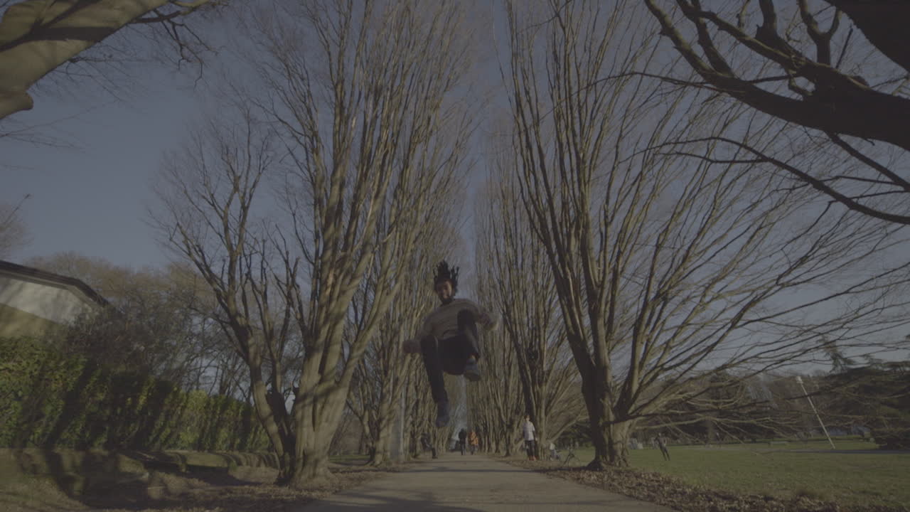 Skateboarder performing a trick in a park with trees