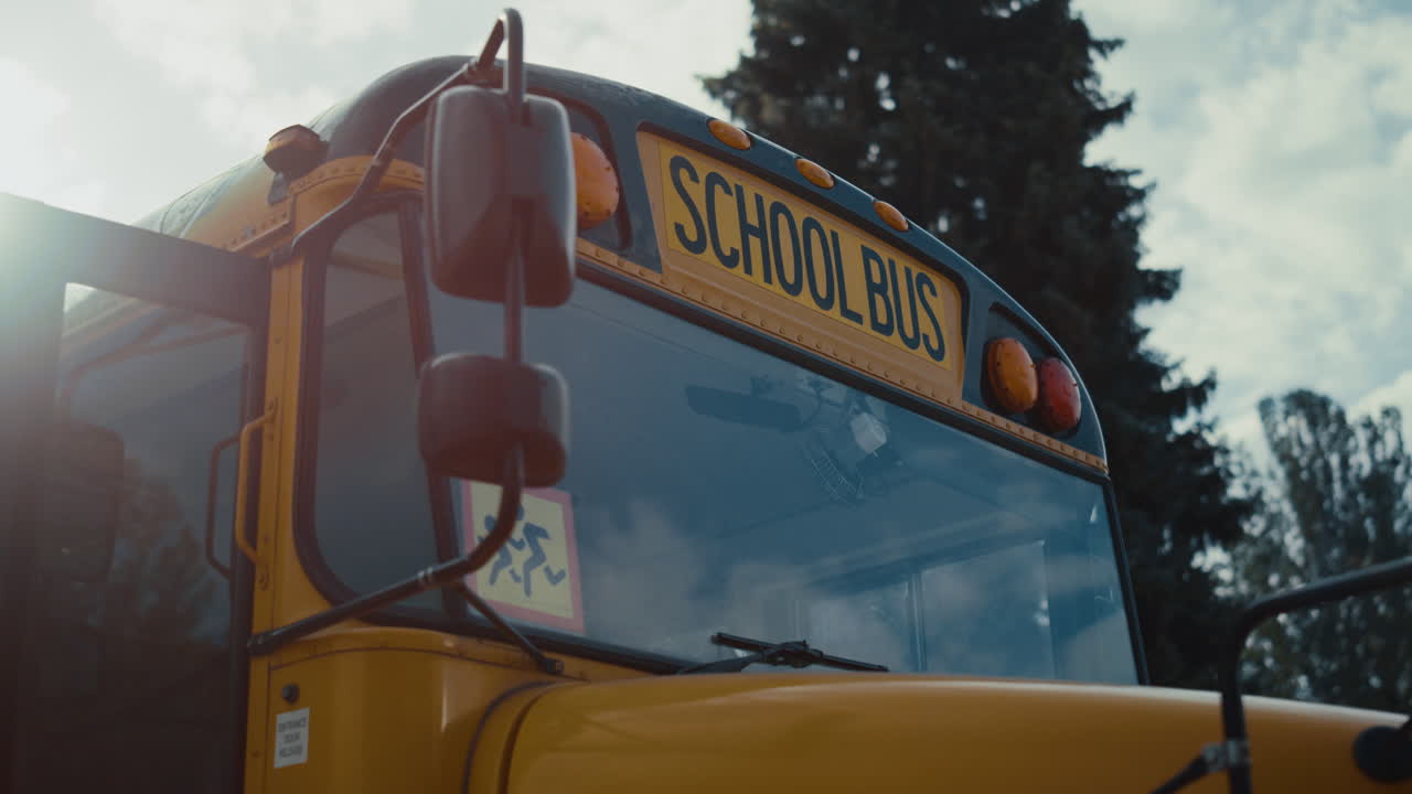 Front view academic bus window with warning sign yellow red headlights close up.