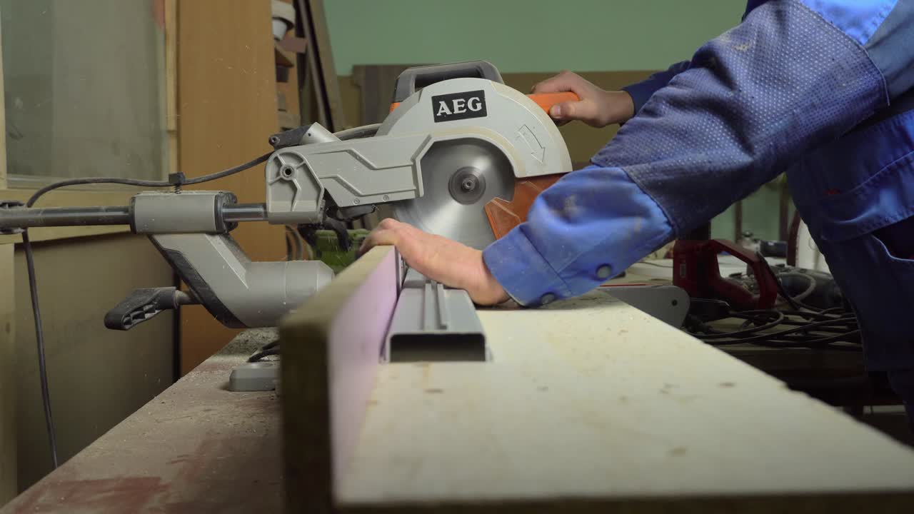 человек режет металлический профиль на режущей машине.