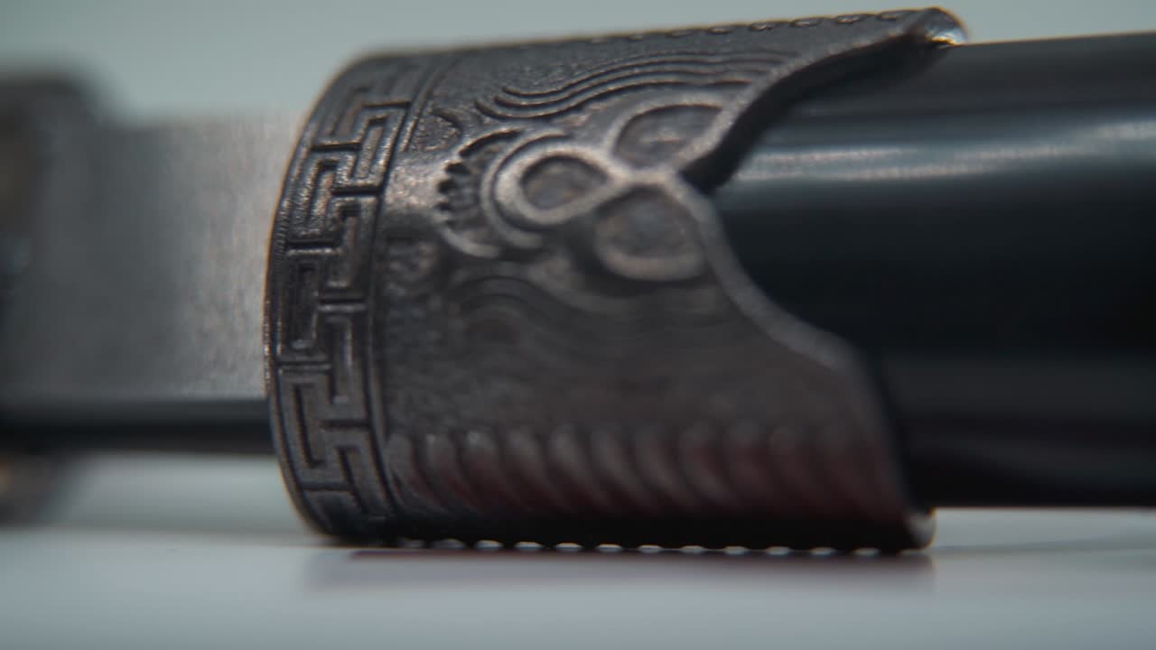 макро-запись двух древних серебряных ножей, закрытых, китайского антикварного оружия, исторического винтажного лезвия, старой текстурированной стали, традиционного кинжала, профессионального освещения, кинематографического замедления 120 кадров в секунду