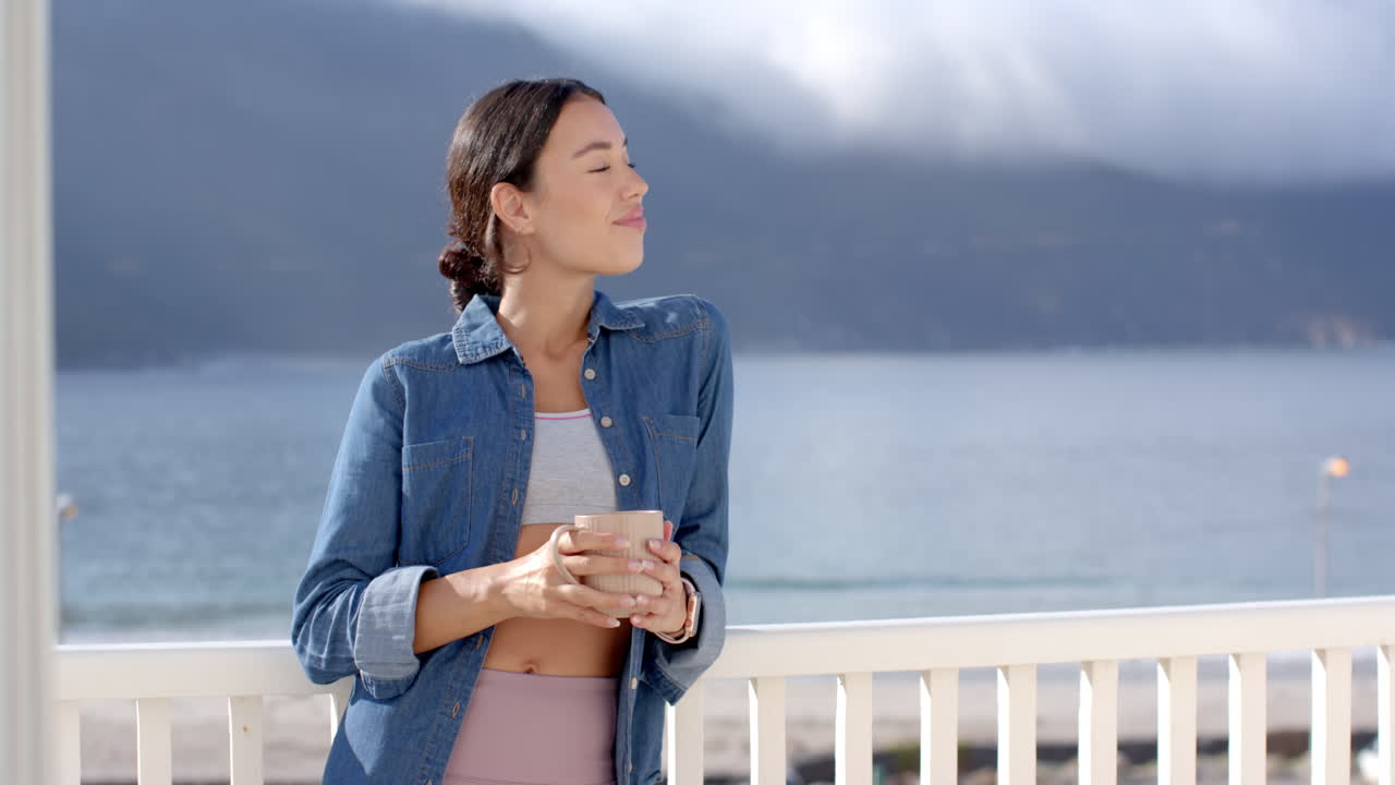 Woman enjoying morning coffee on balcony, overlooking serene ocean view, copy space