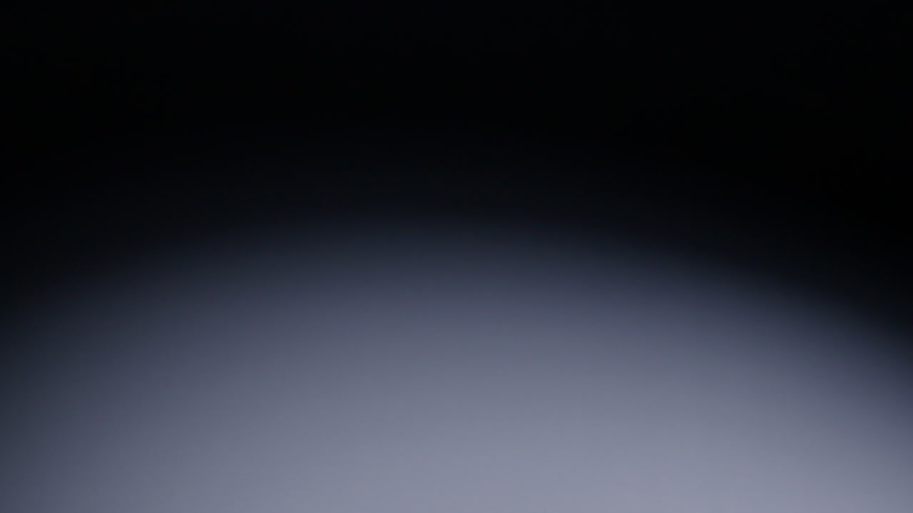 Slow-motion wide shot of red die falling into middle of screen and rolling out of shot to screen right