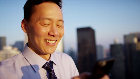 asian businessman using technology on rooftop at sunrise