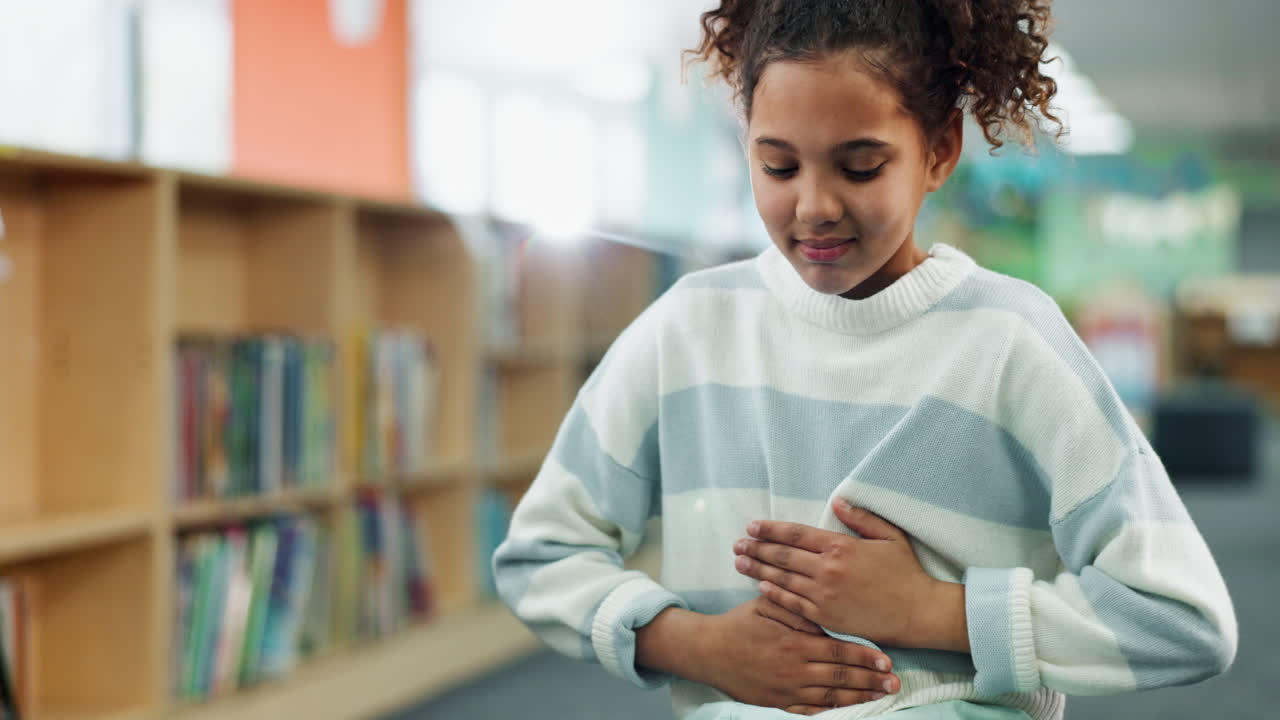 A young girl experiencing a stomach ache in a library