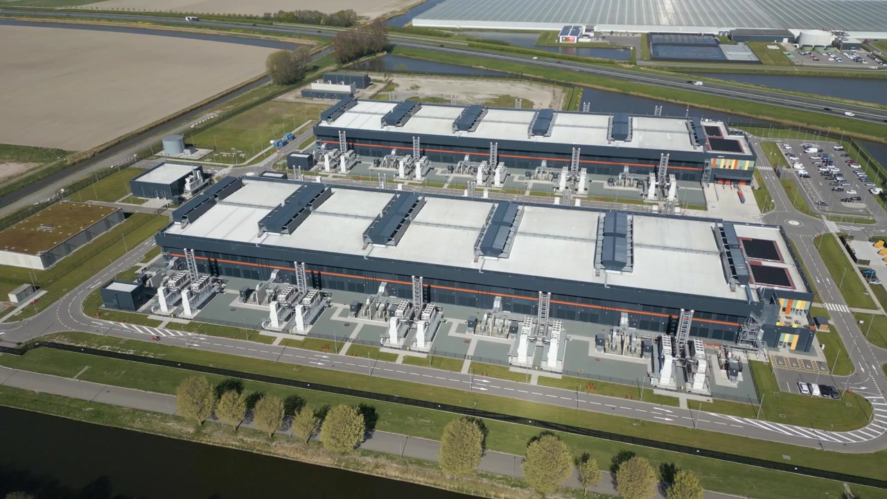 Højt luftperspektiv af et massivt campus for cloud computing og serverinfrastruktur i det hollandske landskab.