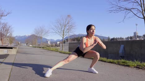 Attractive-fit-young-woman-doing-side-lunges-exercising-outdoors