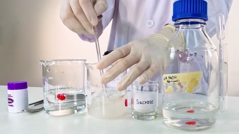 a scientist mixes clear and colored solutions in beakers using a pipette in a lab setting.