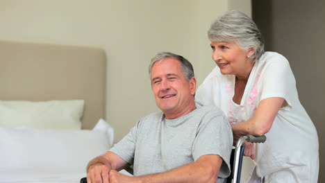 man in wheelchair and wife watching something and laughing