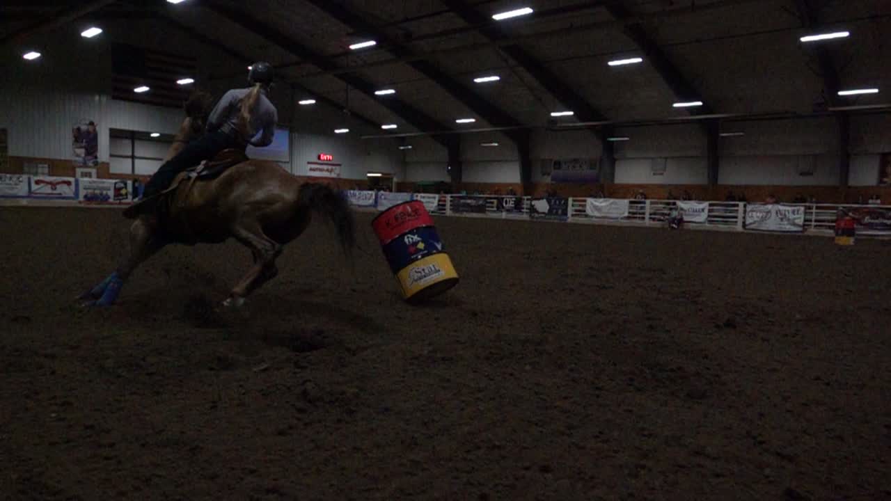 Cámara lenta de caballo y jinete compitiendo en una carrera de barriles